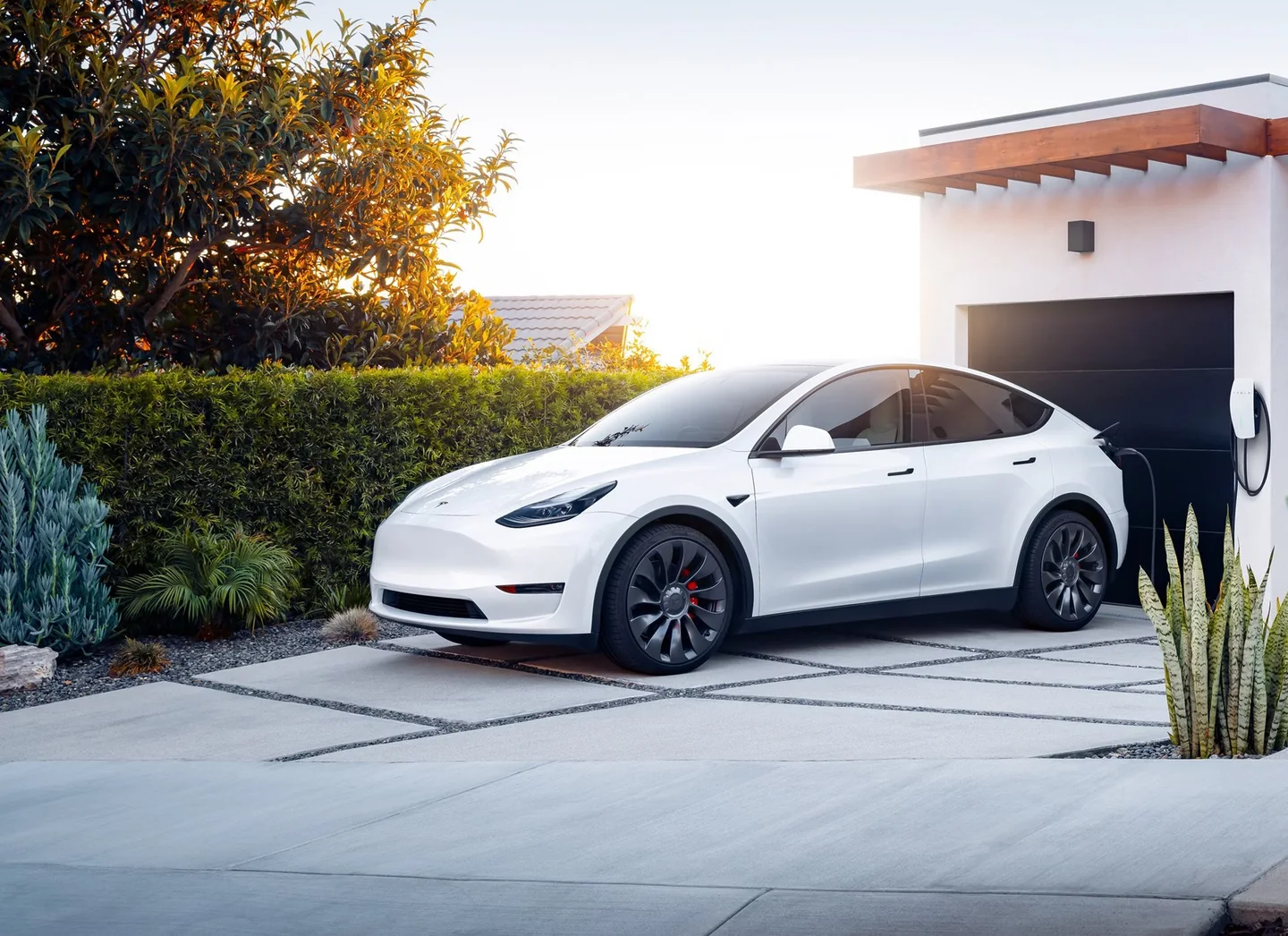 White electric vehicle charging outside a modern Southern California home
